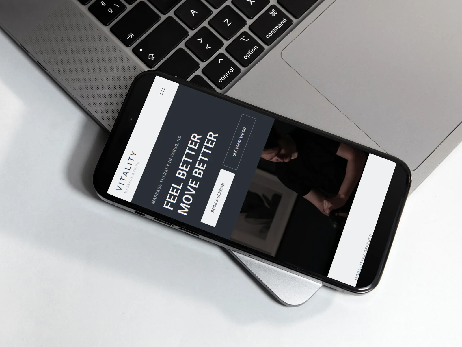 The Vitality home page on a phone, resting on a laptop